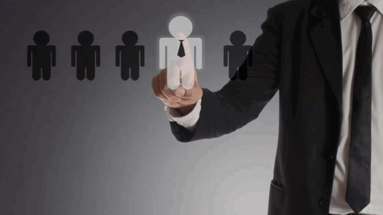 A man in a suit and tie points at a group of people, likely discussing PPC strategies at a local agency.