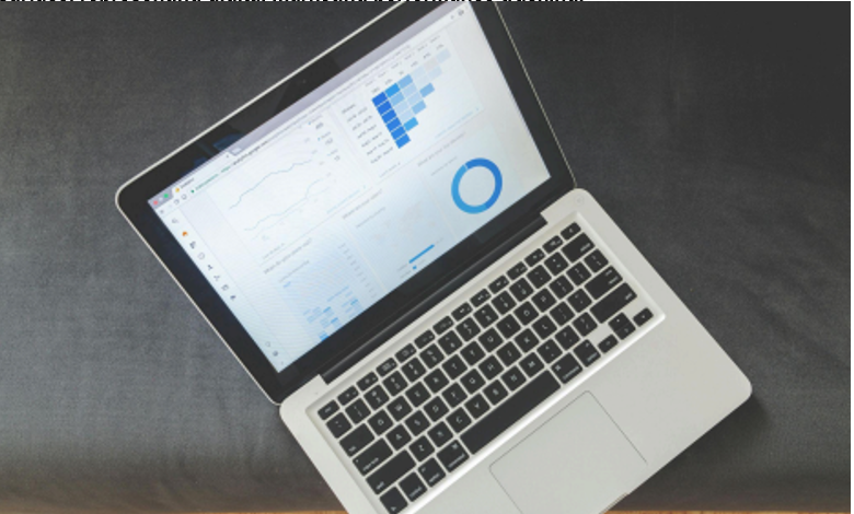 Laptop displaying data analytics dashboard with charts and graphs on a dark surface, representing digital marketing performance tracking.