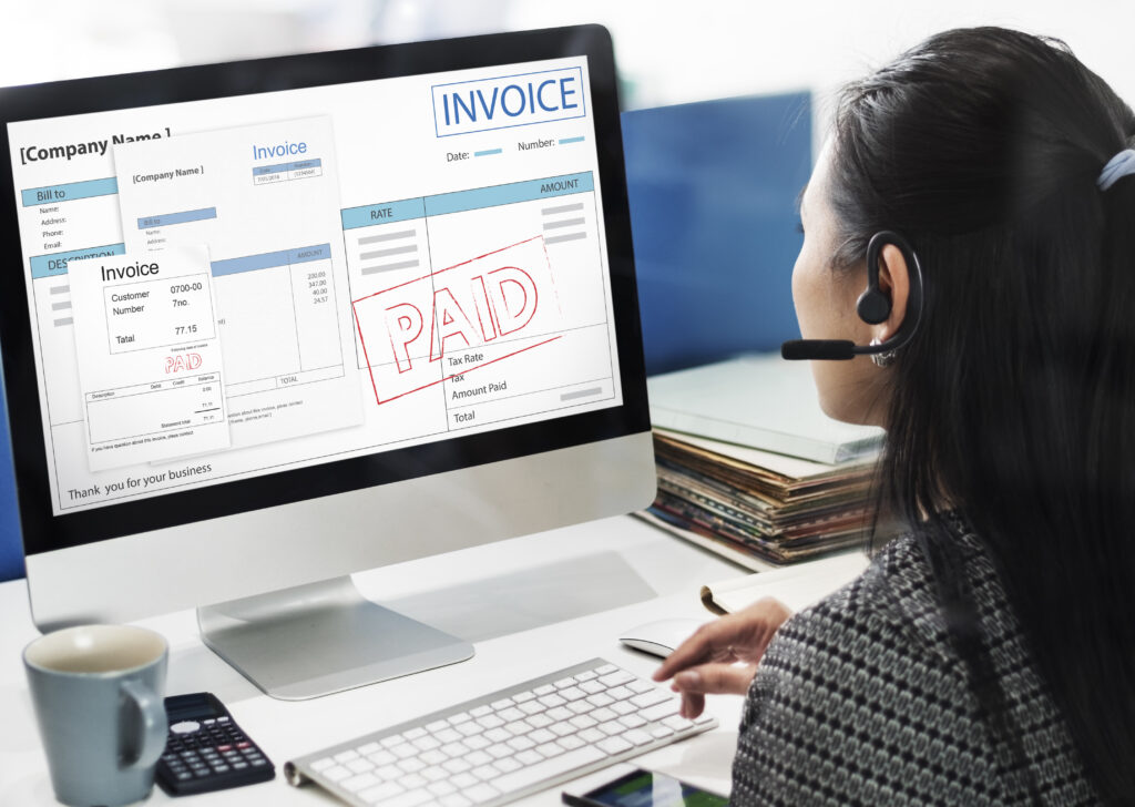 Woman viewing paid invoices on a desktop monitor at work.